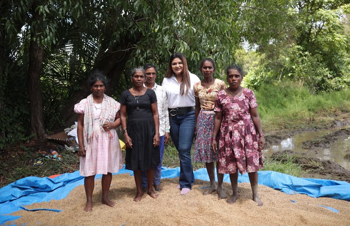 A group of women standing together on harvested paddy in a field
